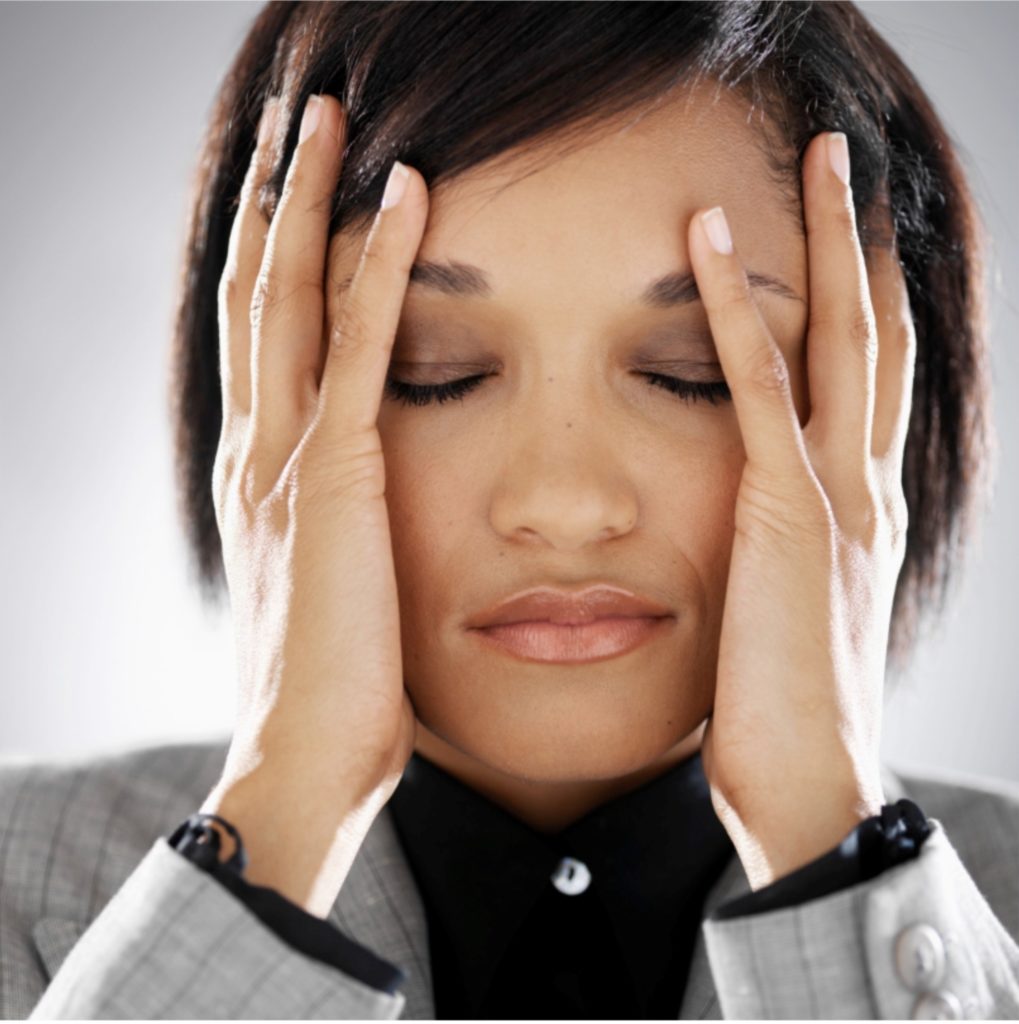 A woman living with tinnitus holds her hands over her ears.